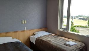 a bedroom with two beds and a window at Tabist Tsukuba Sky Hotel in Tsukuba
