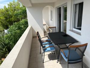 a balcony with a black table and chairs at Apartments MiaMaja in Novalja