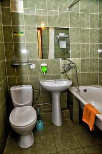 a bathroom with a toilet and a sink and a tub at Green City Hotel in Mykolaiv