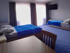 a bedroom with two beds and a table and a dining room at Arkadia in Podgajek