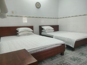 two twin beds in a room with a clock on the wall at Ngoc Mai 1 Hotel in Can Tho