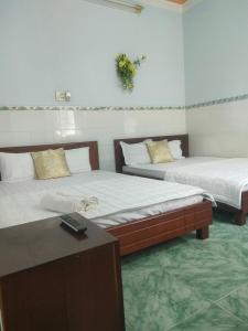 a room with two beds and a table with a remote control at Ngoc Mai 1 Hotel in Can Tho