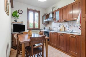 a kitchen with wooden cabinets and a table and a television at Casa Vacanza Rocchetti with Parking&Garden! in Porcari
