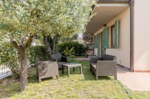 a patio with chairs and a table and a tree at Casa Vacanza Rocchetti with Parking&Garden! in Porcari