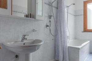 a white bathroom with a sink and a shower at Casa Vacanza Rocchetti with Parking&Garden! in Porcari