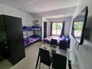 Habitación pequeña con mesa, sillas y literas. en Large New Studio Up to 6 Pax, en Cebú