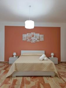 1 dormitorio con 1 cama con pared de color naranja en Montelepre Sweet Home casa vacanze, en Montelepre
