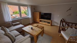 a living room with a couch and a tv and a table at Fischerhaus Lemkenhafen in Lemkenhafen auf Fehmarn