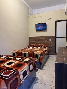 3 camas en una habitación con TV en la pared en Hotel MARU Pool & Events, en Chachalacas