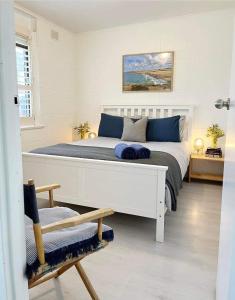 een slaapkamer met een groot wit bed met blauwe kussens bij Bay Breeze Cottage in Encounter Bay