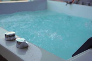 a swimming pool with blue water and two devices at Cozy Haven with Jacuzzi, Rooftop in Bandung