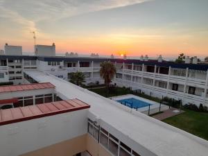 una vista aérea de un edificio con la puesta de sol en el fondo en Apartamento 335 Hotel Flamero en Matalascañas