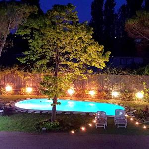 科里亞諾的住宿－Villa con Piscina，一座晚上带两把椅子和一棵树的游泳池