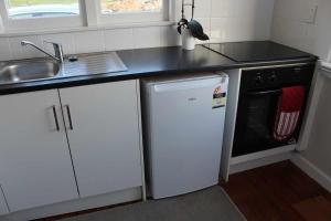 uma pequena cozinha com um lavatório e uma máquina de lavar louça em The Suite - Huntly House em Auckland