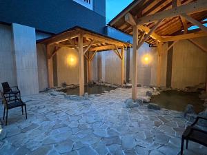 un patio de piedra con un pabellón de madera en un edificio en Hotel Route Inn Grand Chichibu, en Chichibu