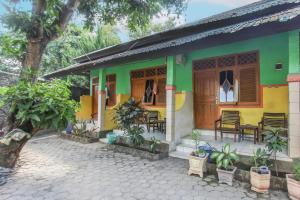 uma casa verde e amarela com cadeiras e mesas em OYO 92908 Hotel Jayanni em Labu Sumbawa