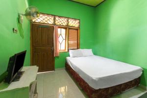 Cette chambre verte comprend un lit et une télévision. dans l'établissement OYO 92908 Hotel Jayanni, à Labu Sumbawa