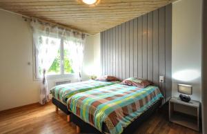 1 dormitorio con 1 cama con edredón a rayas y ventana en La rose des champs, en Ramerupt