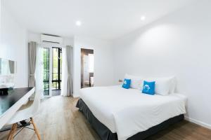 a white bedroom with a large bed and a desk at Blu Monkey Bed & Breakfast Phuket - SHA Plus in Phuket