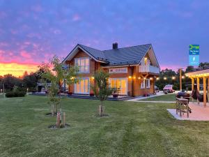 a house with trees in the yard with a sunset at Karukella puhkemaja in Lyuganuse