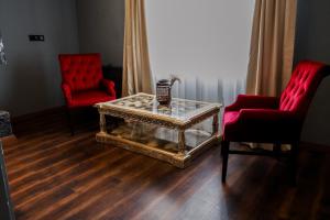 a living room with two red chairs and a coffee table at Adess Otel in Çekme