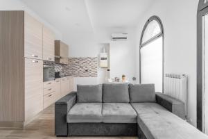 ein Wohnzimmer mit einer grauen Couch in einer Küche in der Unterkunft OR34 Sesto San Giovanni- Bright House - in Sesto San Giovanni
