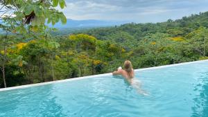 una mujer en una piscina con vistas a un bosque en Casa Libertinn, en Manuel Antonio