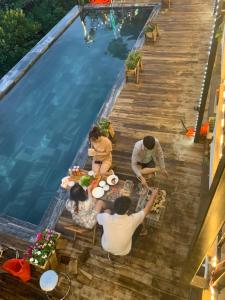 un grupo de personas sentadas en una mesa junto a una piscina en Nắng Homestay, en Tam Ðảo