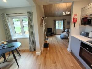 a living room with a table and a kitchen at Breckland Lodge 1 with Hot Tub in Belladrum