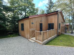 a log cabin with a porch and a deck at Breckland Lodge 1 with Hot Tub in Belladrum