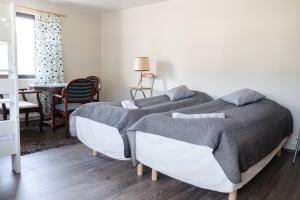 two beds in a bedroom with a table and chairs at Bed & Breakfast Restaurang Sybarit in Houtskari +16 photos