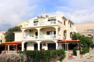 a white building with a balcony on top of it at Apartments and rooms by the sea Pag - 3152 in Pag