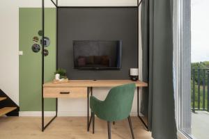 a desk with a television and a green chair at Airport Studio Zarembowicza by Renters in Wrocław