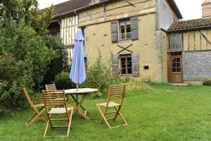 a table and chairs with an umbrella in a yard at Les tavillons in Soulaines-Dhuys