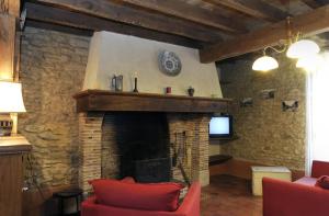 a living room with a stone fireplace and a tv at Les tavillons in Soulaines-Dhuys
