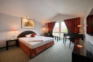 a hotel room with a bed and a desk at Hotel Lechnerhof Unterföhring in Munich