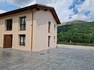 ein Gebäude mit einer großen Terrasse vor einem Berg in der Unterkunft Apartamentos Villa de Panes - La Plaza in Panes