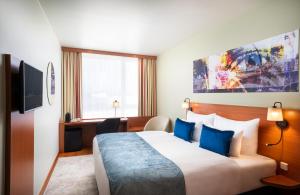 Una habitación de hotel con una cama grande con almohadas azules. en Leonardo Hotel Salzburg Airport, en Salzburgo