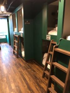 a room with three bunk beds and a hard wood floor at Wasabi Mita Hotel in Tokyo
