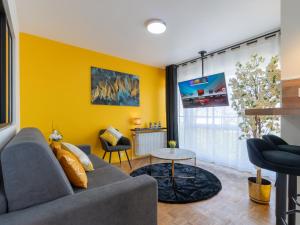 a living room with a couch and a yellow wall at LE CELESTE - HYPERCENTRE PARKING ET NETFLIX GRATUITS PROCHE TRAMWAY ET PARC DE LA TETE D'OR in Villeurbanne