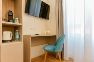 a room with a blue chair and a tv at Aqua Comfort Rooms - Eja Sardinia in Cagliari