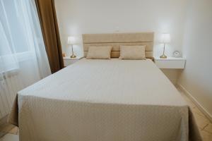 a bedroom with a large white bed with two lamps at Apartman 007 in Vukovar