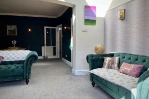 uma sala de estar com duas cadeiras verdes e um sofá em The Lytham Cottage em Lytham St Annes