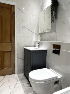 a white bathroom with a toilet and a sink at The Lytham Cottage in Lytham St Annes
