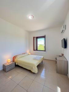 1 dormitorio con 1 cama, ventana y TV en Villa Cecita Holiday, en Sellia Marina