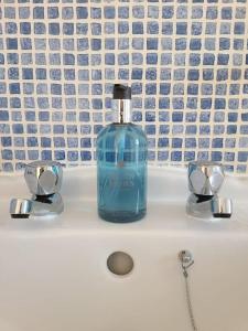 a blue bottle of soap sitting on top of a sink at 2 Bedroom apartment in Brean in Brean