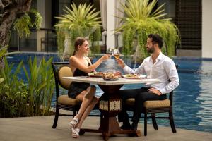 Un uomo e una donna seduti a un tavolo con un bicchiere di vino di The Trans Resort Bali a Seminyak
