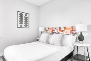 um quarto branco com uma grande cama branca com almofadas em CozySuites Music Row Charming 1BR free parking 49 em Nashville
