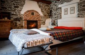 een slaapkamer met 2 bedden en een open haard bij Chalet in pietra e legno con caminetto in Inverso Pinasca