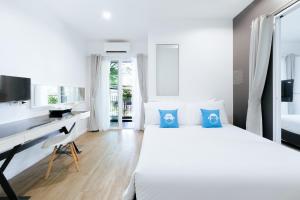 a white bedroom with a desk and a bed at Blu Monkey Bed & Breakfast Phuket - SHA Plus in Phuket Town